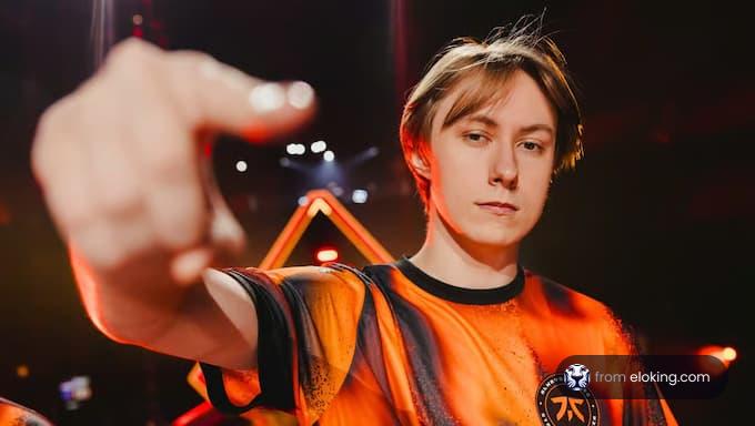 An esports player pointing in an orange jersey.