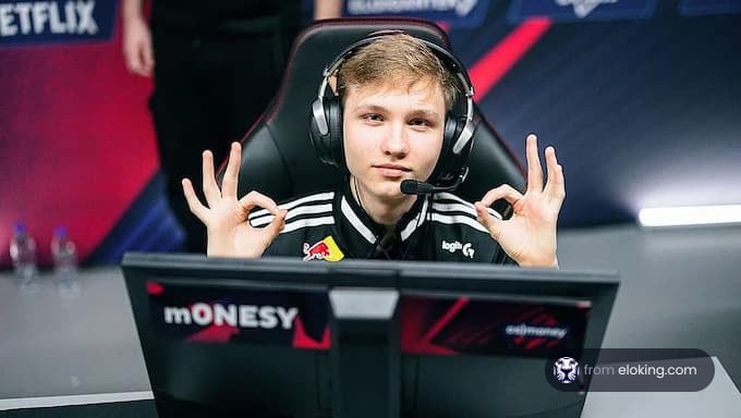 A young esports player giving a thumbs up gesture in front of a computer.