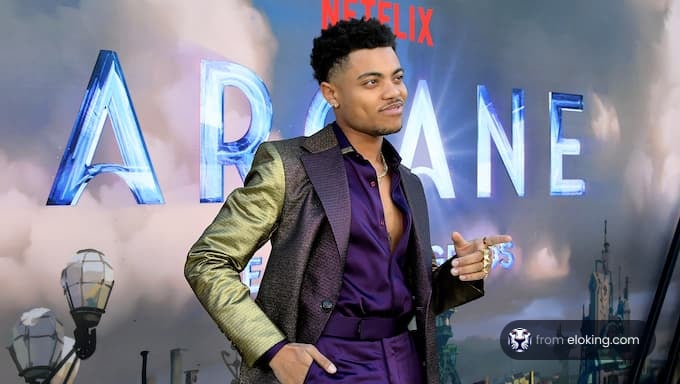 Homme souriant à l'événement de première d'Arcane avec le logo Netflix en arrière-plan