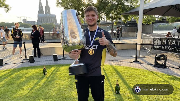 Man holding a large trophy smiling outdoors with a cathedral in the background