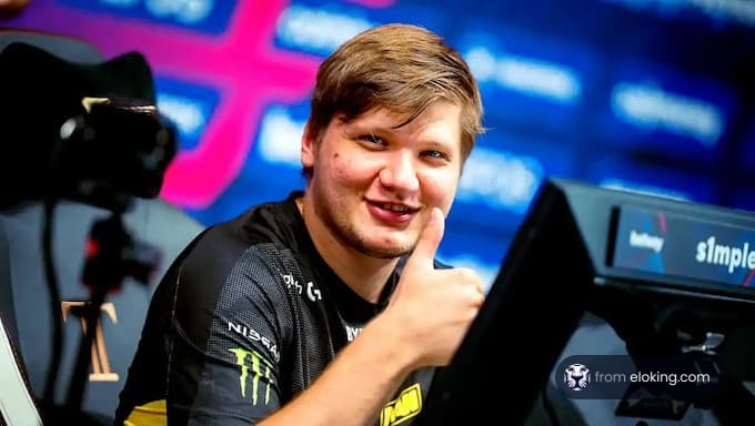 Professional gamer giving a thumbs up while sitting in front of a computer monitor at an esports event