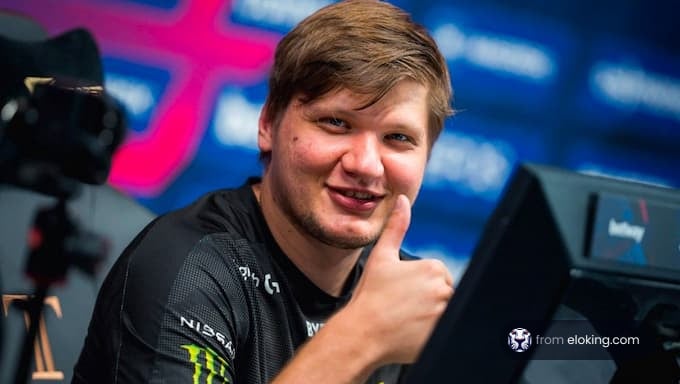 Professional gamer giving a thumbs up while sitting at a computer during an esports tournament