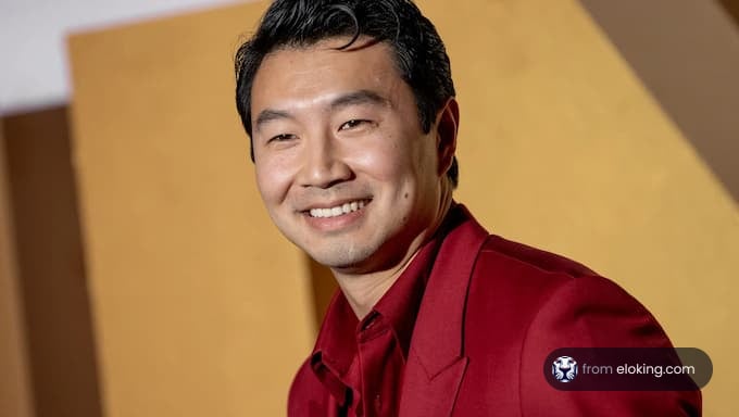 A smiling man in a red jacket at an event.