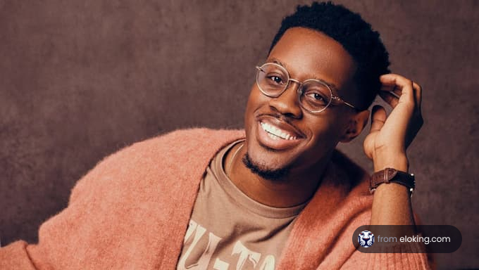 A smiling man wearing a pink sweater.