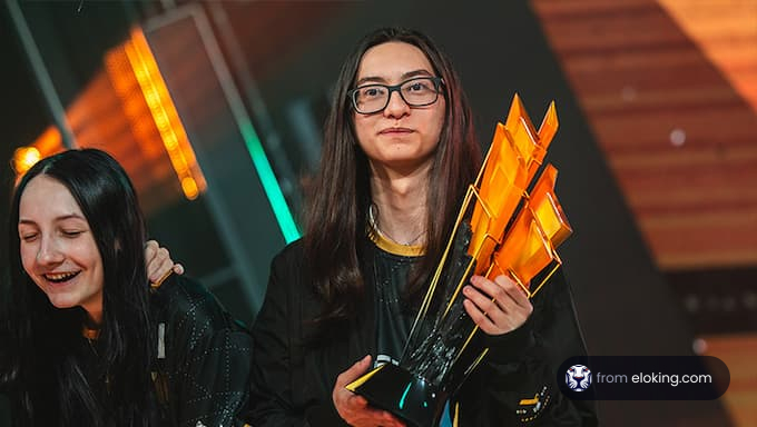 Two women celebrating with a trophy at an esports event