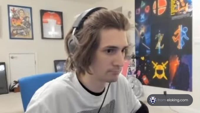 Young man gaming in a room decorated with posters and a blue chair