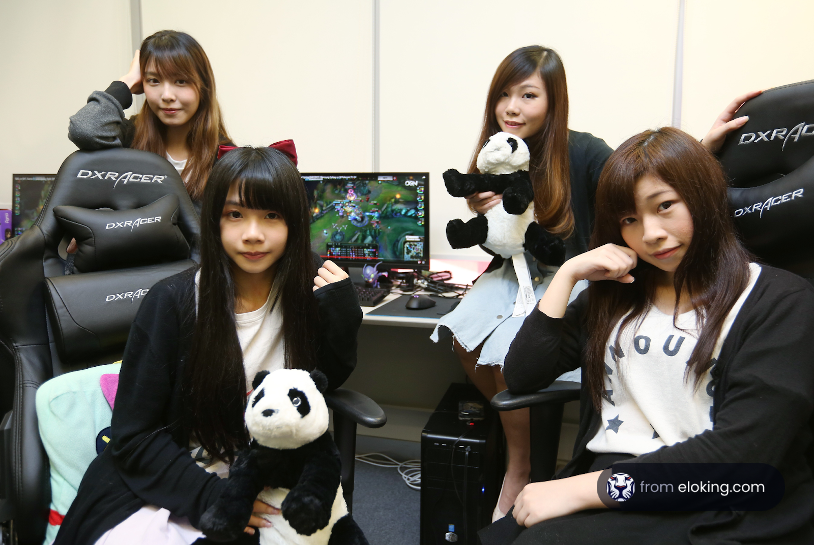 Young women posing with computer gaming setups and plush toys